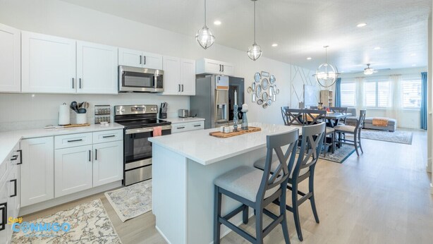 A modern kitchen with white cabinets, stainless steel appliances, and a central island with bar stools. - Near American Fork Canyon | Family & Pet Friendly (American Fork)