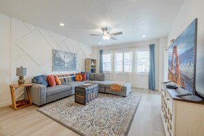 A modern living room with a grey sofa, a patterned rug, and a television on a wooden cabinet. - Near American Fork Canyon | Family & Pet Friendly (American Fork)