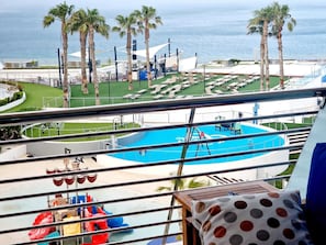 A pool area with slides, palm trees, and a view of the sea.