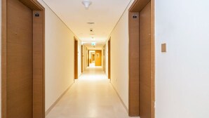 Un pasillo largo y estrecho de hotel con puertas de madera a ambos lados y piso de color claro.