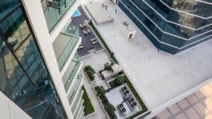 Un edificio moderno con fachada de vidrio, zona de estar al aire libre y terraza en la azotea.