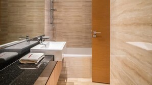 Un baño moderno con una encimera negra, dos lavamanos, una ducha y una puerta de madera.