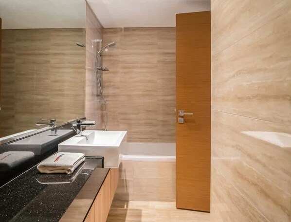 A modern bathroom with a black countertop, two sinks, a shower, and a wooden door. - Luxury Missoni Branded 1BR in Business Bay (Dubai)
