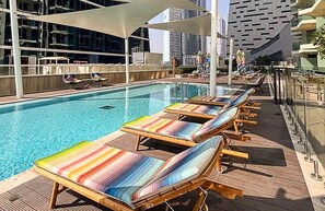 A rooftop pool area with lounge chairs and a view of the city skyline. - Homesgetaway-cozy Luxury 1BR I Missoni Urban Oasis (Dubai)