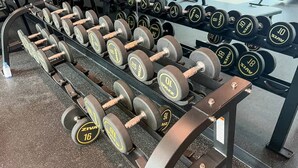 A gym with rows of dumbbells on racks, a mirror, and exercise equipment in the background. - Stylish Missoni-branded Studio (Dubai)