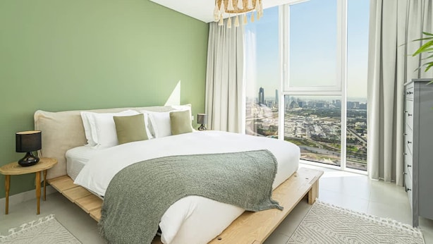 A modern bedroom with a large bed, a city view, and a green wall. - Homesgetaway Spacious 2BR Apartment in Al Wasl 1 Residences (Dubai)