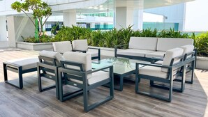 A modern outdoor seating area with a glass-top coffee table, white cushioned chairs, and a sofa. - Homesgetaway Spacious 2BR Apartment in Al Wasl 1 Residences (Dubai)