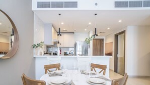 A modern dining area with a round table, chairs, and a kitchen in the background. - Homesgetaway Spacious 2BR Apartment in Al Wasl 1 Residences (Dubai)
