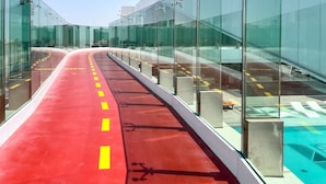 A red pathway with yellow lines, glass walls, and concrete pillars. - Homesgetaway Spacious 2BR Apartment in Al Wasl 1 Residences (Dubai)