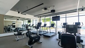 A modern gym with treadmills, elliptical machines, and weight stations. - Homesgetaway-luxury 2Br Apartment in Beach Vista Tower 2 With Beach Access (Dubai)
