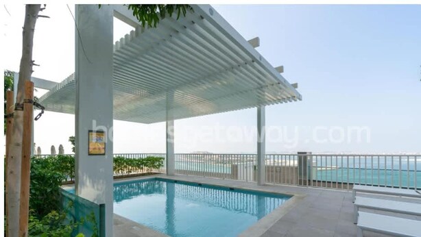 A swimming pool with a pergola, a view of the sea, and a tiled deck area. - Homesgetaway-luxury 2Br Apartment in Beach Vista Tower 2 With Beach Access (Dubai)