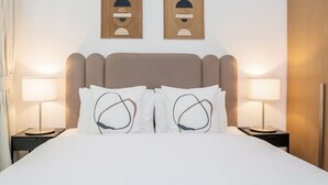 Een hotelkamer met een groot bed, twee bedlampjes en twee wandlampen.