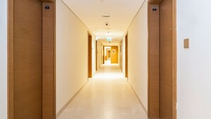 A long, narrow hotel corridor with wooden doors on both sides and a light-colored floor. - Business Bay - 1BR Missoni Branded Apartment (Dubai)