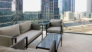 A modern balcony with a sofa and armchairs, offering a city view. - Business Bay - 1BR Missoni Branded Apartment (Dubai)
