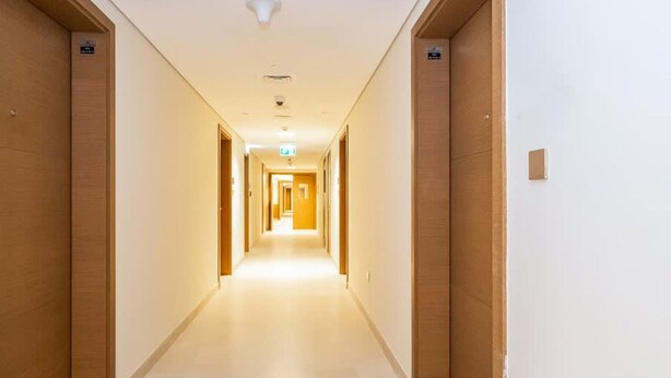 Ein Hotelgang mit Holztüren, Fliesenboden und einer Deckenleuchte.