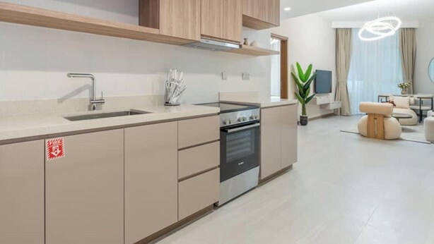 A modern kitchen with a built-in oven, a stainless steel sink, and wooden cabinets. - 1BR on Dubai Canal 5 Mins to Burj Dubai Mall (Dubai)