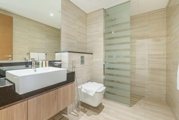 A modern bathroom with a large sink, a glass shower enclosure, and a wooden vanity. - 1BR on Dubai Canal 5 Mins to Burj Dubai Mall (Dubai)