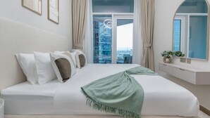 A modern hotel room with a large bed, a view of the city through floor-to-ceiling windows, and a minimalist decor. - 1BR on Dubai Canal 5 Mins to Burj Dubai Mall (Dubai)