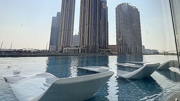 Blick auf hohe Gebäude, im Vordergrund ein Schwimmbecken.