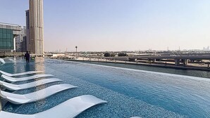 A rooftop infinity pool with a view of a city skyline, including a tall building. - Sophisticated 2BR Missoni Home in Business Bays Prime Location (Dubai)