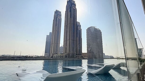 A swimming pool with modern, sleek lounge chairs and a view of tall buildings in the background. - Sophisticated 2BR Missoni Home in Business Bays Prime Location (Dubai)