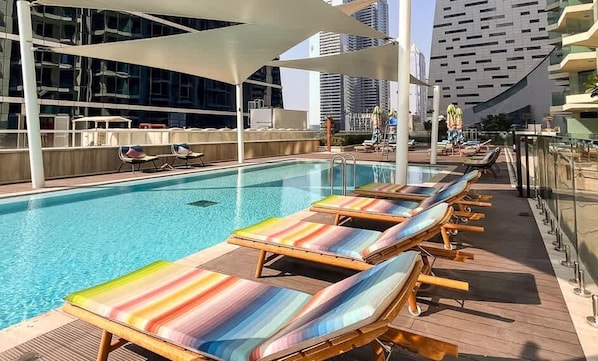 Une piscine sur le toit, dotée de chaises longues et offrant une vue sur les bâtiments modernes.