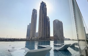 A swimming pool with modern, sleek lounge chairs and a view of tall buildings in the background. - 2BR Missoni Branded 5 Mins to Burj Dubai Mall (Dubai)