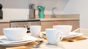 A kitchen with white bowls, spoons, and a stove. - Sophisticated Studio Escape Missoni Luxury Design (Dubai)