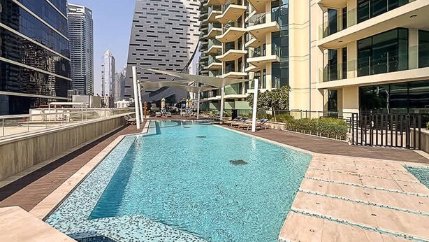 A swimming pool area with a view of high-rise buildings in the background. - 2BR Missoni Apt 5 min Drive to Burj Dubai Mall (Dubai)