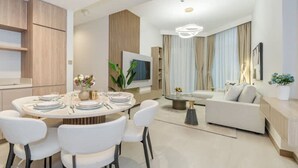 A modern living room with a sofa, a coffee table, and a dining area with a round table and chairs. - 2BR Missoni Apt 5 min Drive to Burj Dubai Mall (Dubai)