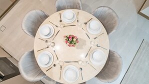 A round dining table with six chairs, a central floral arrangement, and a light-colored floor. - 2BR in Missoni Bldg 5 Mins to Burj Dubai Mall (Dubai)