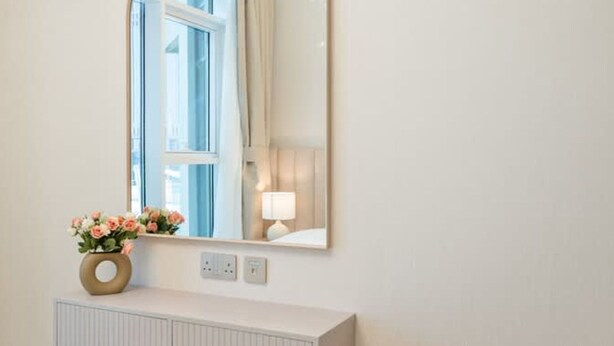 A bathroom with a mirror, a vase of flowers, and a radiator. - 2BR in Missoni Bldg 5 Mins to Burj Dubai Mall (Dubai)