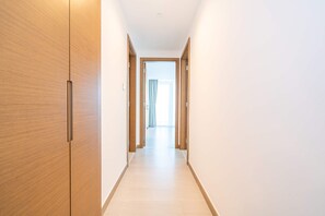 A hallway with wooden doors, a light-colored floor, and a view into another room with a window and curtains. - Stunning 2BR Missoni High-floor Breathtaking Views (Dubai)