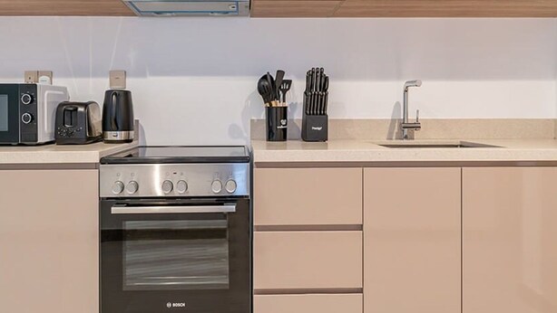 Una cocina con horno Bosch, tostadora, cafetera y bloque de cuchillos.