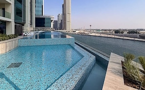 Une piscine sur le toit offrant une vue sur les gratte-ciel de la ville et un plan d’eau.