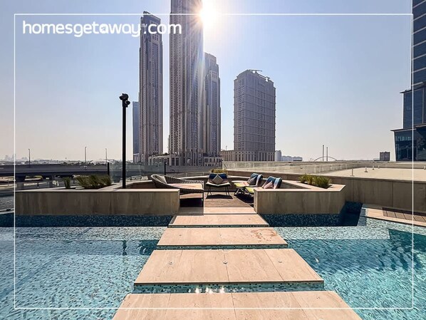 A rooftop pool with lounge chairs and a clear view of tall buildings in the background. - Stylish 2BR Fully Furnished Unit at Missoni (Dubai)