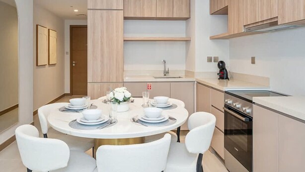 A modern kitchen with a central island, built-in cabinets, and a stainless steel oven. - Stylish 2BR Fully Furnished Unit at Missoni (Dubai)