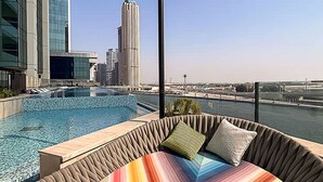 A rooftop pool area with a view of a city skyline, including a tall building. - 2-br Missoni Luxury With Stunning Lake View (Dubai)