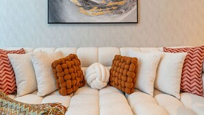 A sofa with a textured white cover, two brown textured pillows, and a colorful woven throw. - 2-br Missoni Luxury With Stunning Lake View (Dubai)