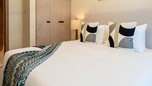 A hotel room with a large bed, a wardrobe, and two framed pictures on the wall. - 2-br Missoni Luxury With Stunning Lake View (Dubai)