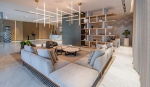 A modern living room with a sectional sofa, round coffee table, and a bookshelf. - Stylish Missoni 1BR Luxury Stay Ideal for 5 Guests (Dubai)
