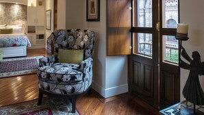 A bedroom with a bed, a chair, a window, and a statue. - Villa Colonna (Quito)