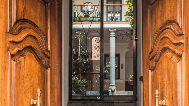 A wooden staircase leading to a door with a wrought iron gate. - Villa Colonna (Quito)