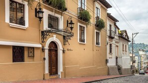 A historic building with a wooden door, arched windows, and a cobblestone street. - Villa Colonna (Quito)