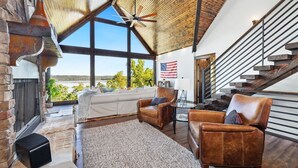 Ein geräumiges Wohnzimmer mit großem Fenster, Kamin, Ledersesseln und einer Treppe.