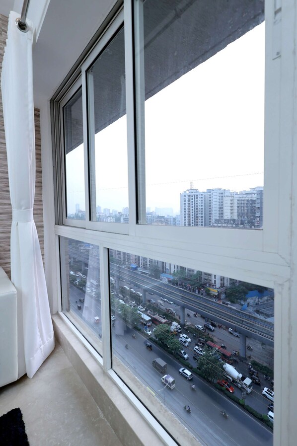 A room with a large window overlooking a busy street and high-rise buildings.