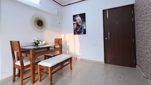 A dining area with a wooden table, chairs, and a bench. There is a wall clock and a framed picture on the wall. - Entire 2 BHK Suite With Kitchen (Mumbai)