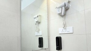 A bathroom with a white sink, a large mirror, a hairdryer, and a telephone. - Entire 2 BHK Suite With Kitchen (Mumbai)