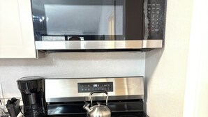 A kitchen with a stainless steel stove, a microwave above it, and a coffee maker on the counter. - Charming  1 bedroom apartment with AC, WiFi in quaint Columbus (Columbus)