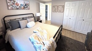 A bedroom with a bed, bedside table, lamp, and a door leading to another room. - Charming  1 bedroom apartment with AC, WiFi in quaint Columbus (Columbus)